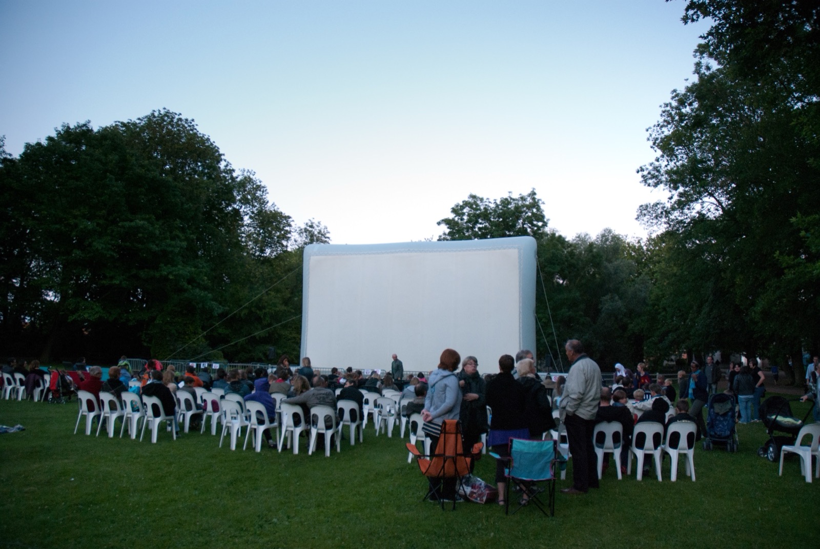 Gigantesco schermo cinematografico gonfiabile «Hallucine» installato in un parco, con il pubblico già accomodato al calar della sera